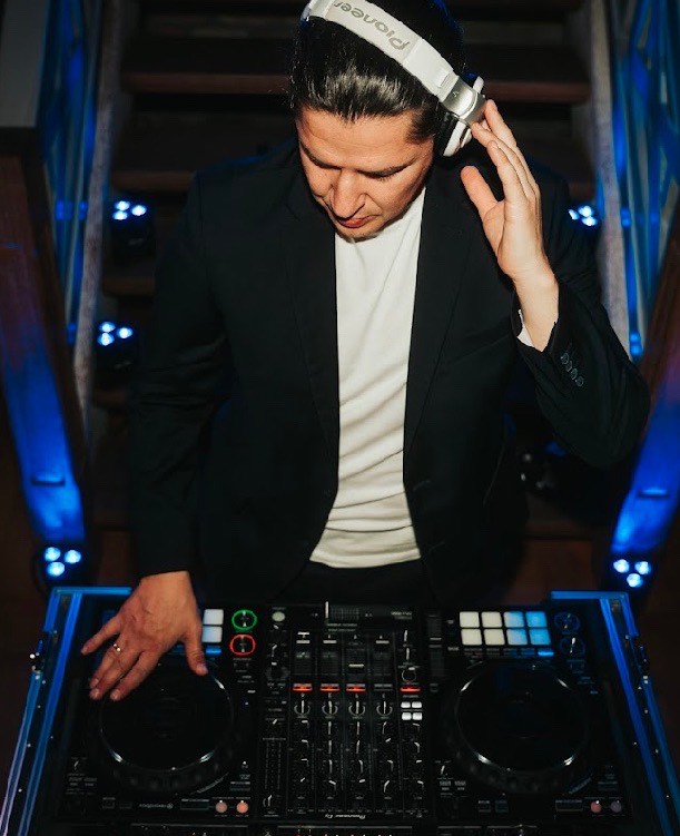 DJ Edouard mit Kopfhörern am DJ-Pult, konzentriert nach unten blickend