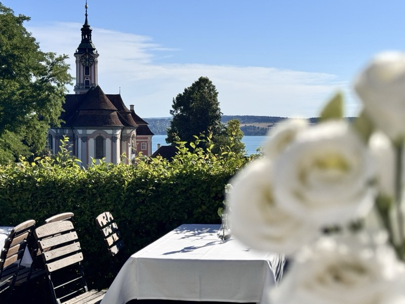 Festlich gedeckte Hochzeitstafel mit weißen Blumen, im Hintergrund die Wallfahrtskirche Birnau und der Bodensee