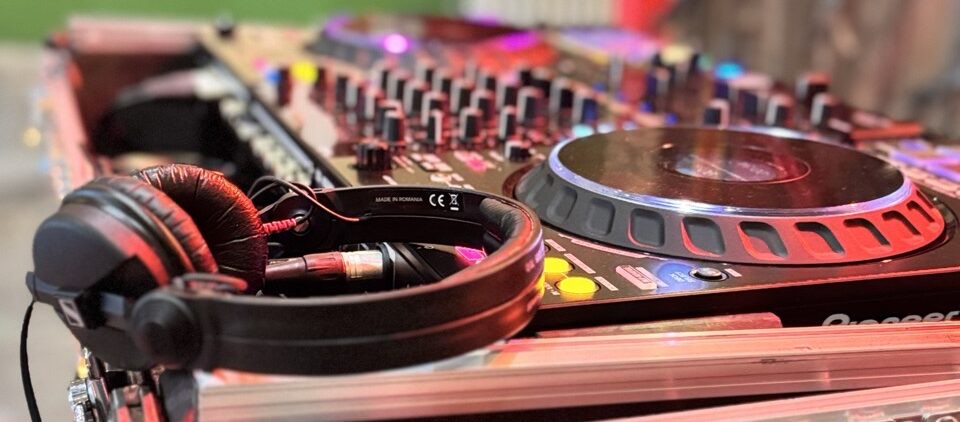 DJ-Controller mit Kopfhörern in buntem Licht, Panoramaaufnahme